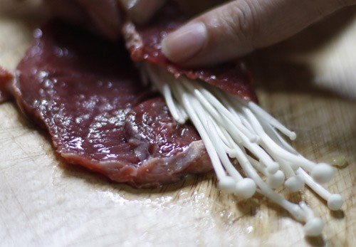 Trải thịt b&ograve; th&aacute;i to bản ra thớt, cho kim ch&acirc;m v&agrave;o cuốn.