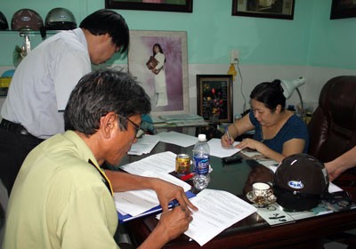Đại diện C&ocirc;ng ty Duy&ecirc;n L&agrave;nh (người phụ nữ - &aacute;o xanh) k&yacute; v&agrave;o bi&ecirc;n bản vi phạm.