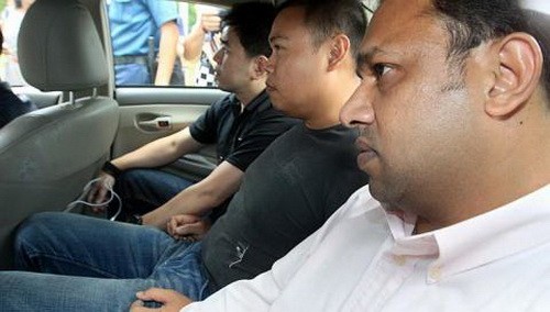 Iskandar Rahmat (giữa) ngồi trong xe với sự canh chừng nghi&ecirc;m ngặt của hai nh&acirc;n vi&ecirc;n cảnh s&aacute;t - Ảnh: therealsingapore.com